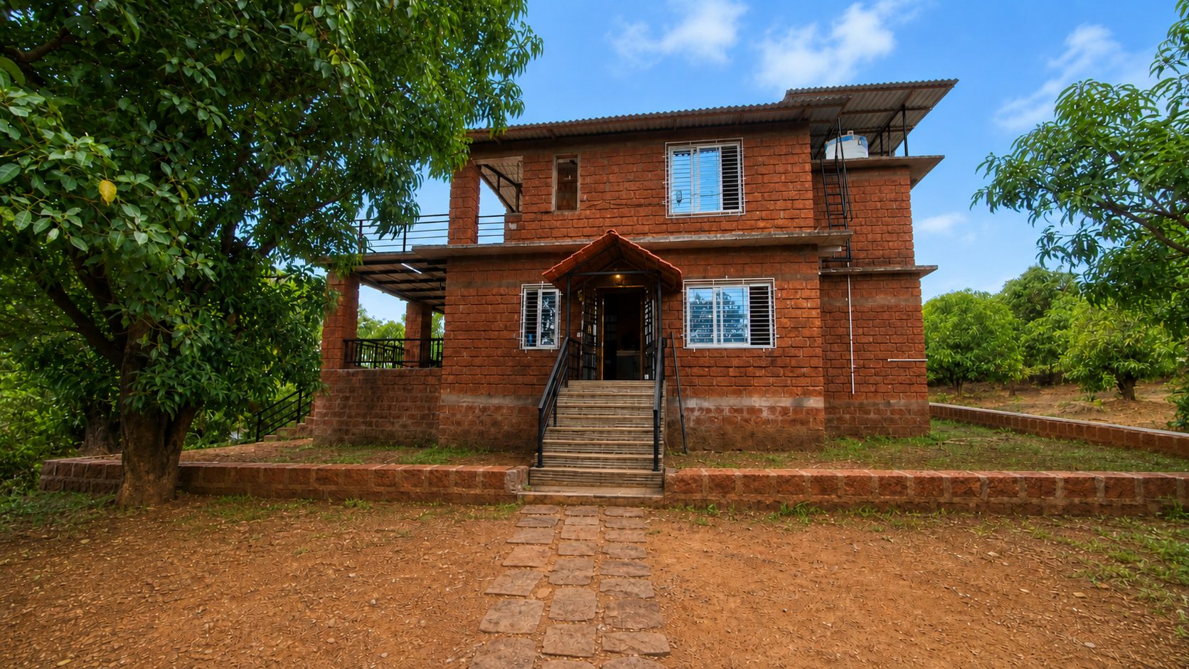Front view of Mango Mount's laterite farmhouse among mango trees